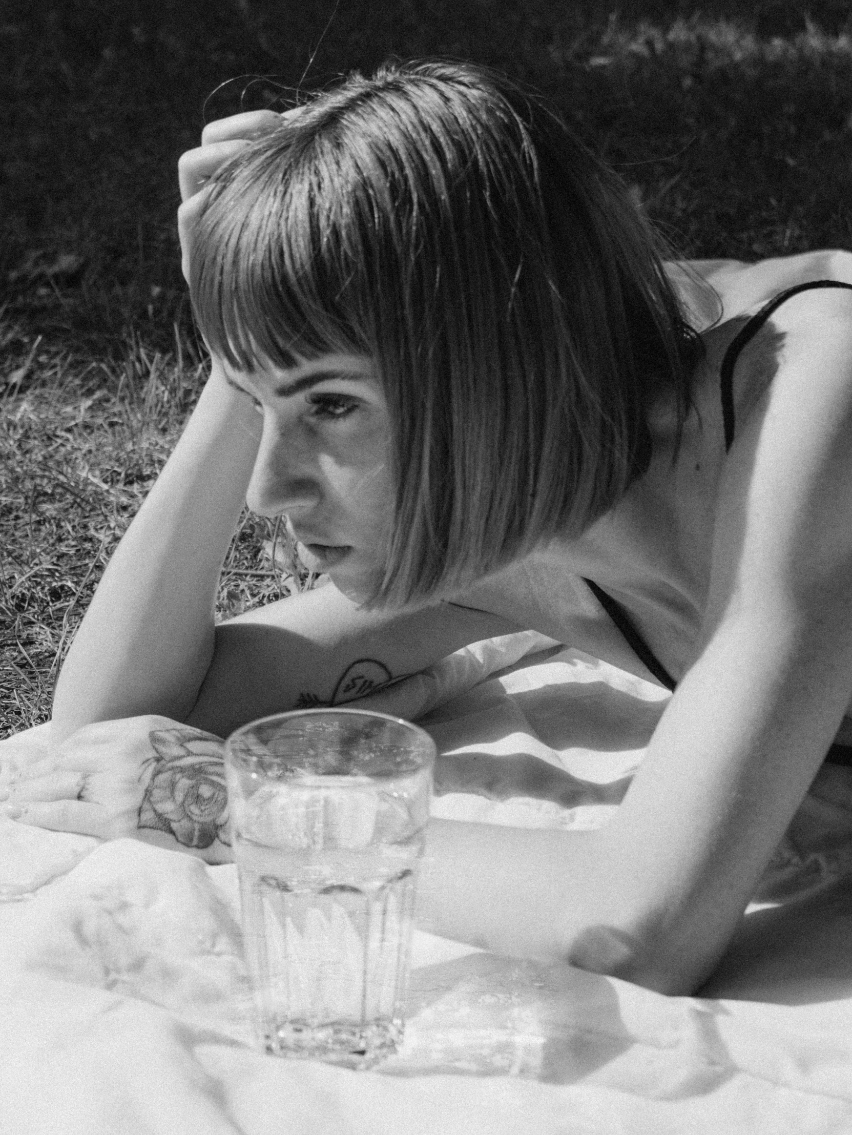 woman laying on blanket with two empty glasses next to a drink