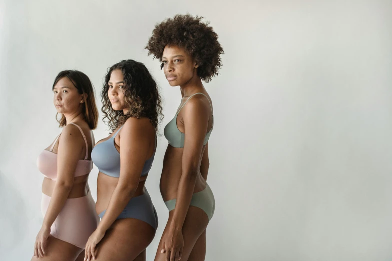 three women in underwear stand in front of a white background