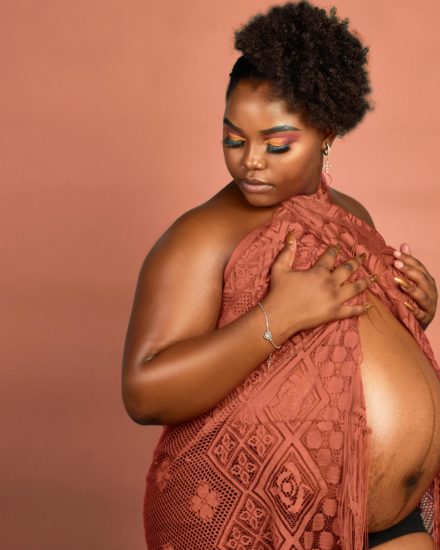 a black woman wears a peach colored knit top