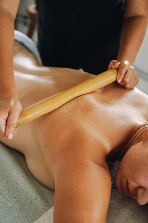 a man getting his back massage with a wooden roller