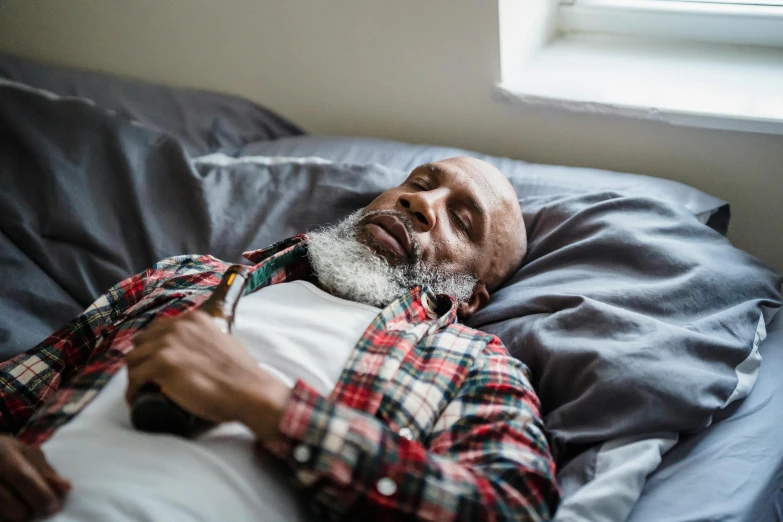 an elderly man is sleeping in bed with his hand on his face