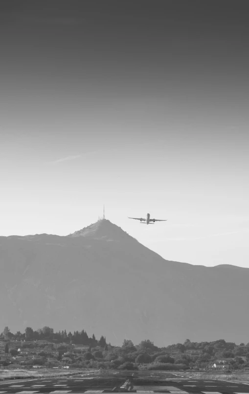 an airplane is flying above the city and mountain