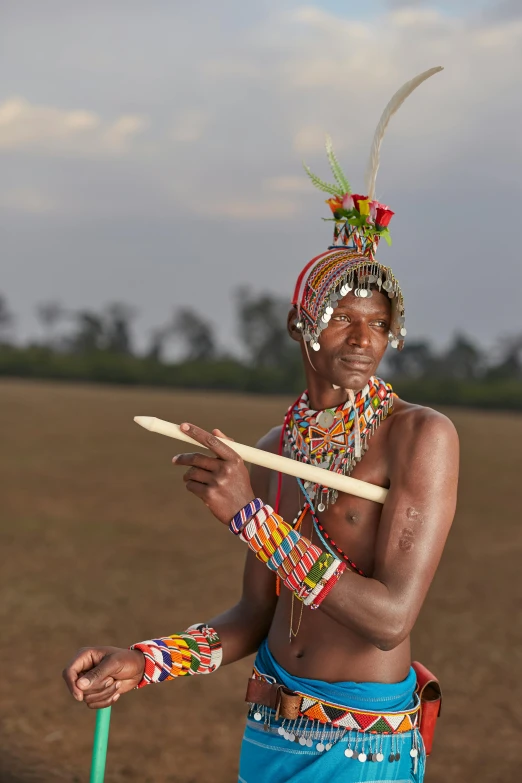 a man in native dress holding up his stick