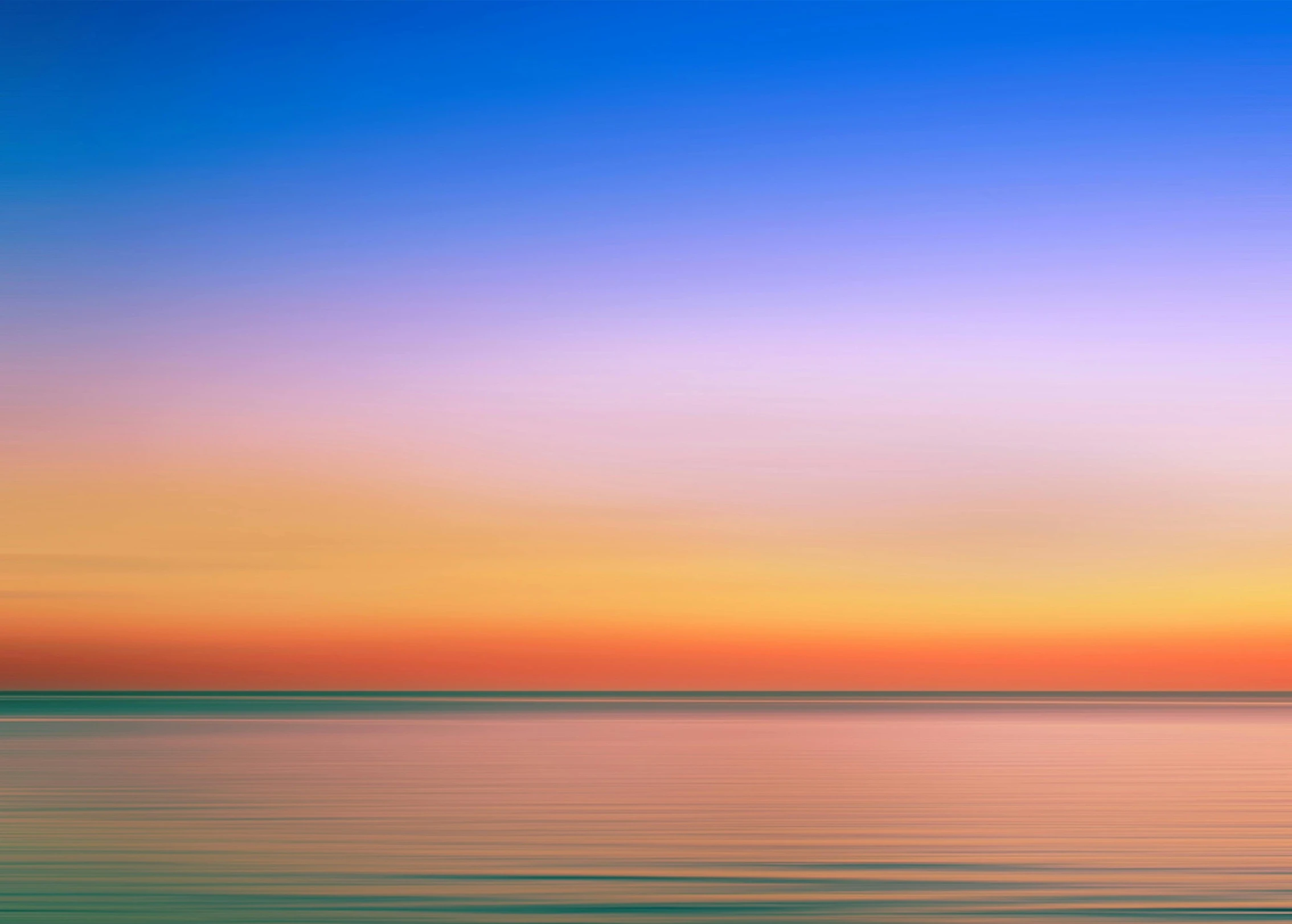 a colorful sky with an ocean in the foreground