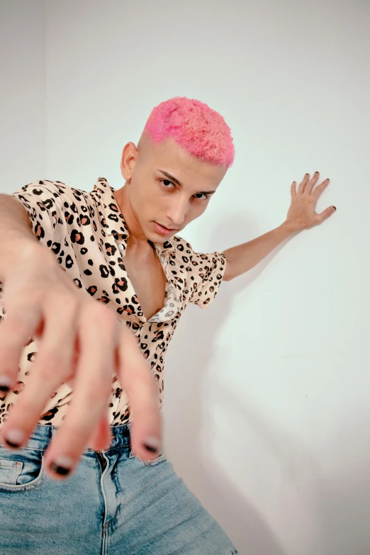 a person with pink hair in a polka dot shirt pointing their finger at the camera