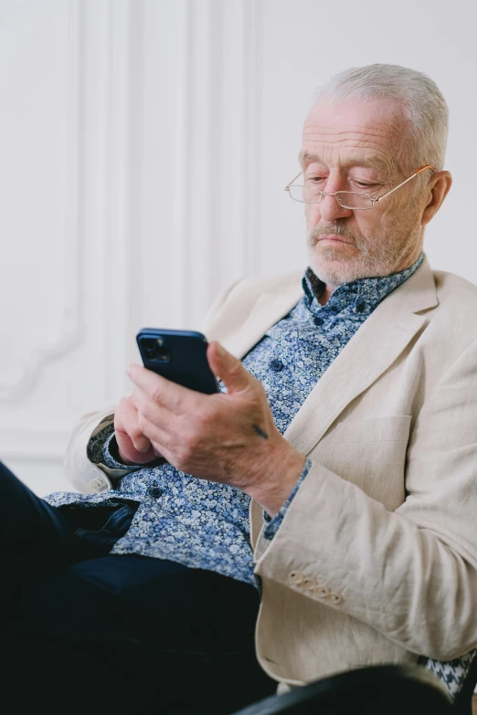 an old man in glasses holds a cellphone