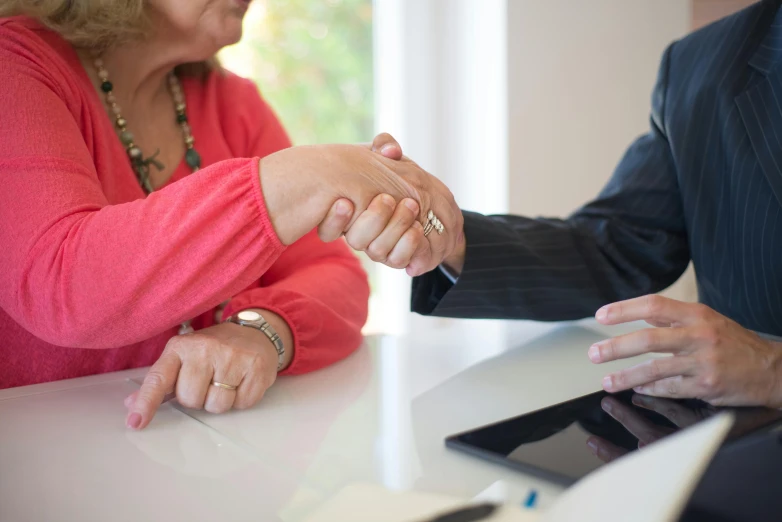 there are two people sitting at a table and one is holding the other's hand