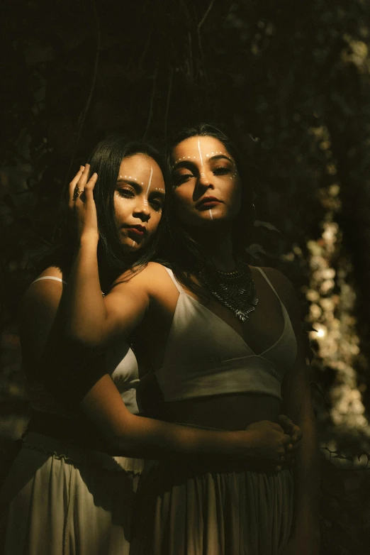 two women are standing near one another in a wooded area