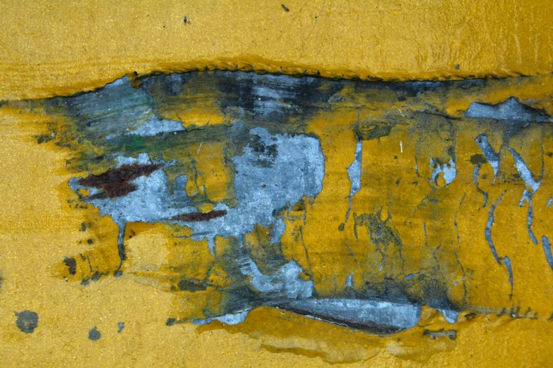 yellow and blue paint chipping on an old, peeling wall