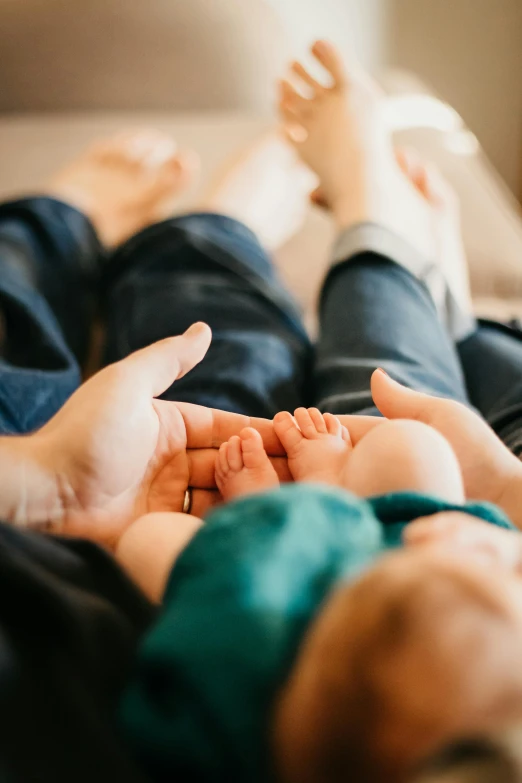 hands of two babies holding each other on the bed