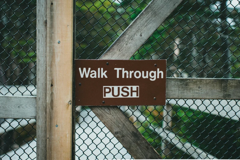 a brown sign that is on a wooden fence