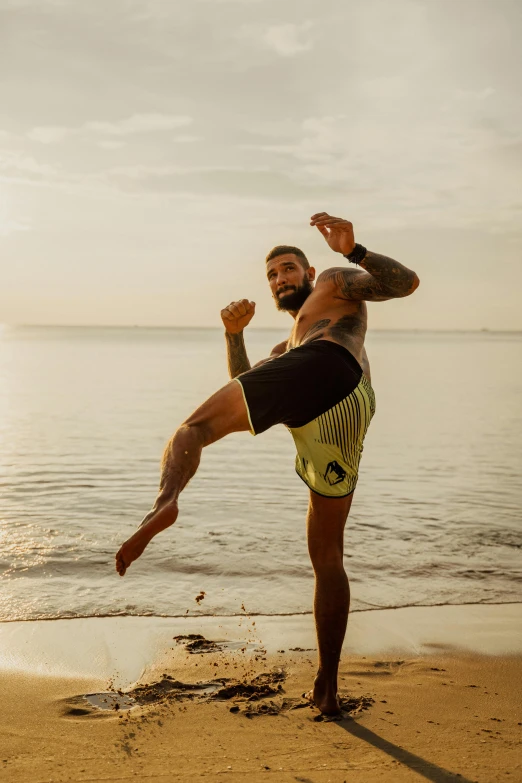 a man doing karate kick on the beach