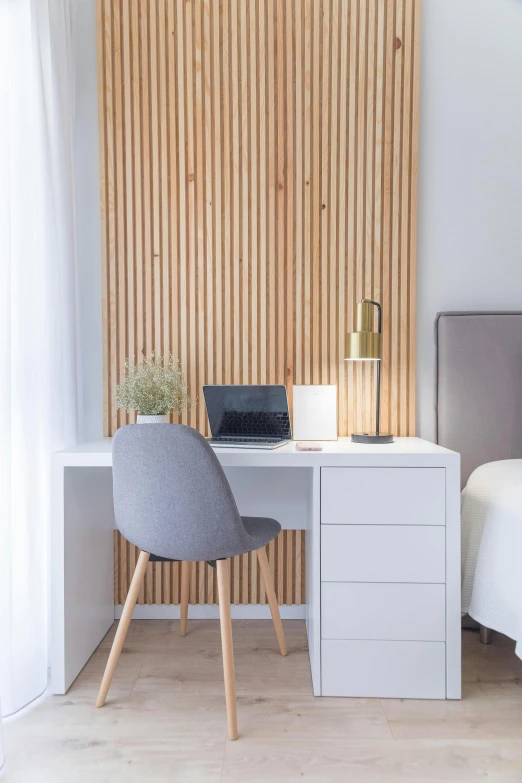 a laptop sits on a small table with a chair beside it