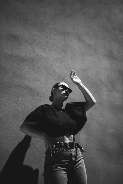 a woman wearing a black shirt and sunglasses stands alone