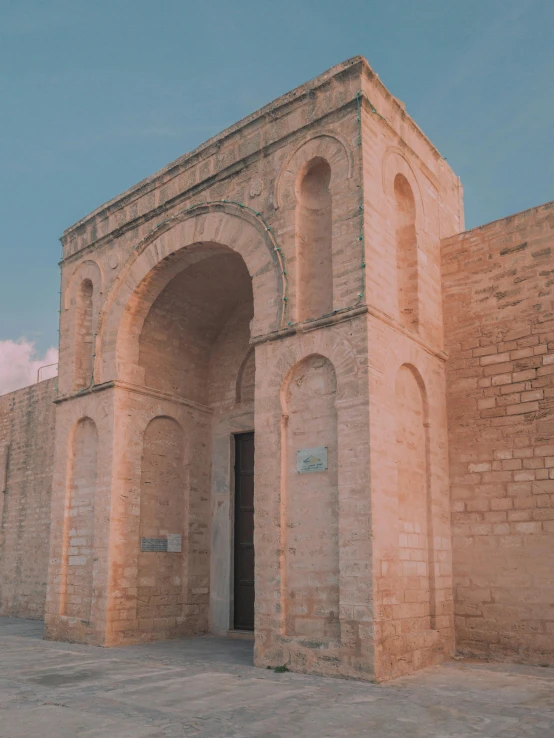 an old brick building with multiple arches, an archway, and some bricks on the sides