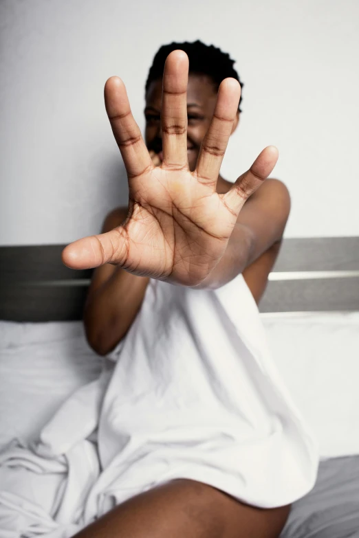 an african american man in bed making the okay sign