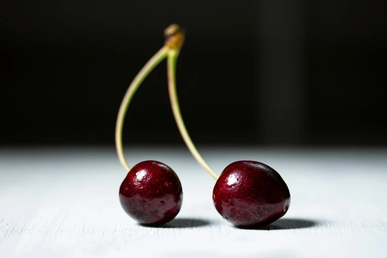 two dark cherries stand on the surface together