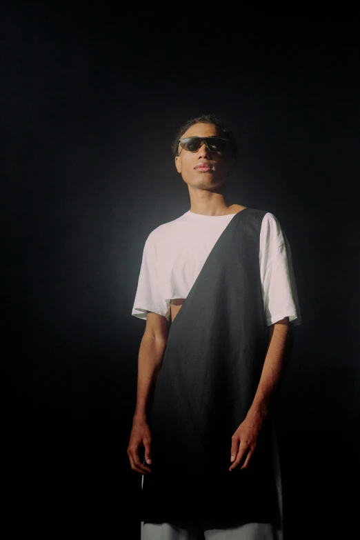 the man wearing shades is standing in front of a dark background