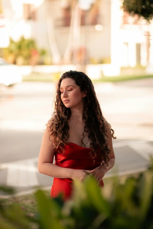 a young woman in a red dress stands in the shade