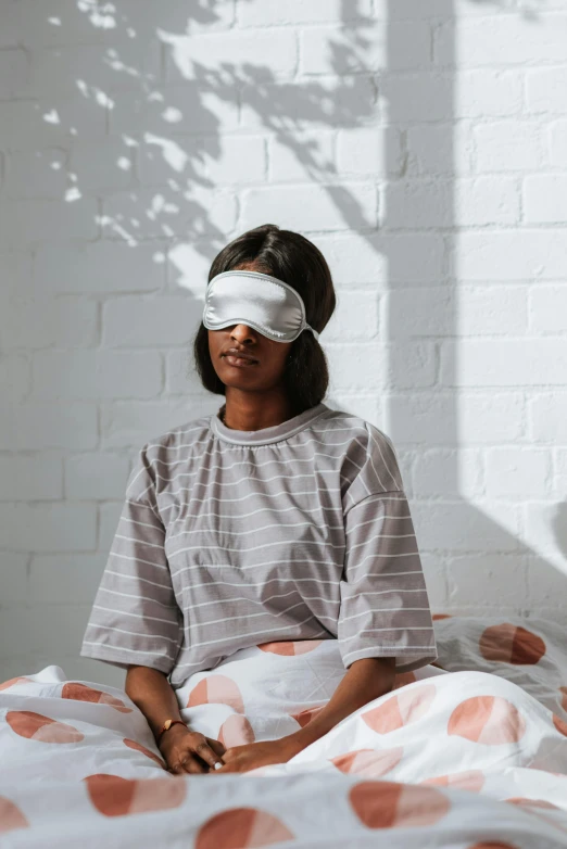 a woman sitting in bed with a blindfold around her eye