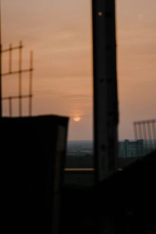 the sun is setting over the ocean with a building in the background