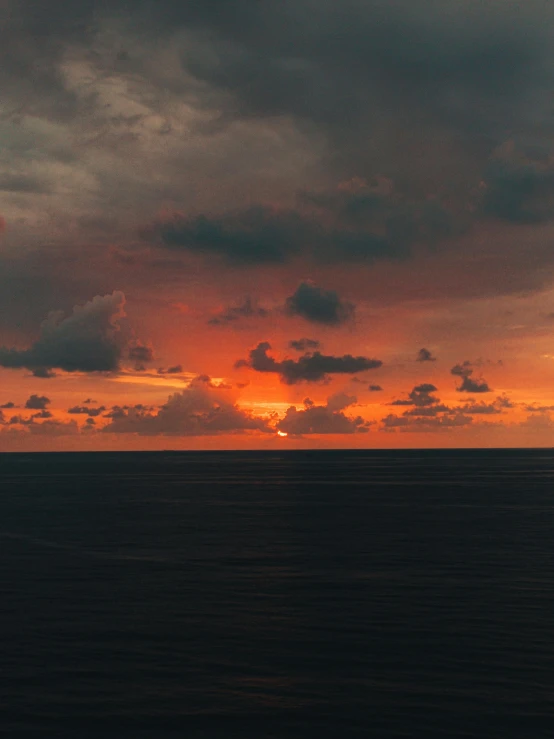 sunset over a large body of water under a cloudy sky