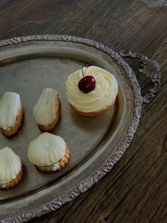 four cupcakes on a tray with a cherry