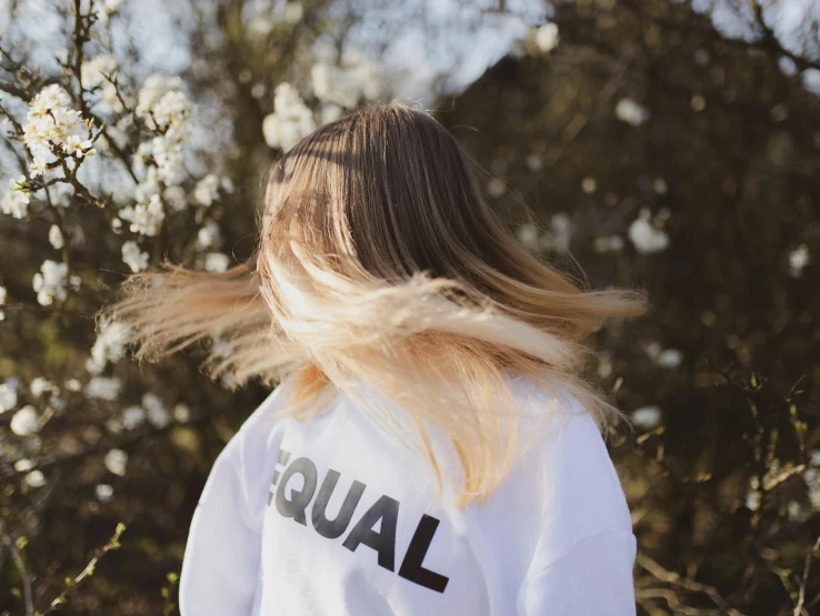 the girl with blond hair wears a white shirt that reads equal