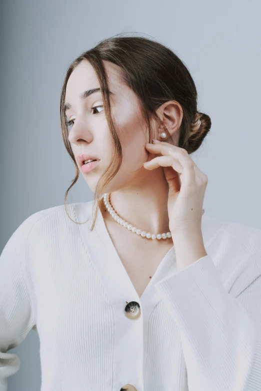 a woman wearing pearl necklace looking up to the side