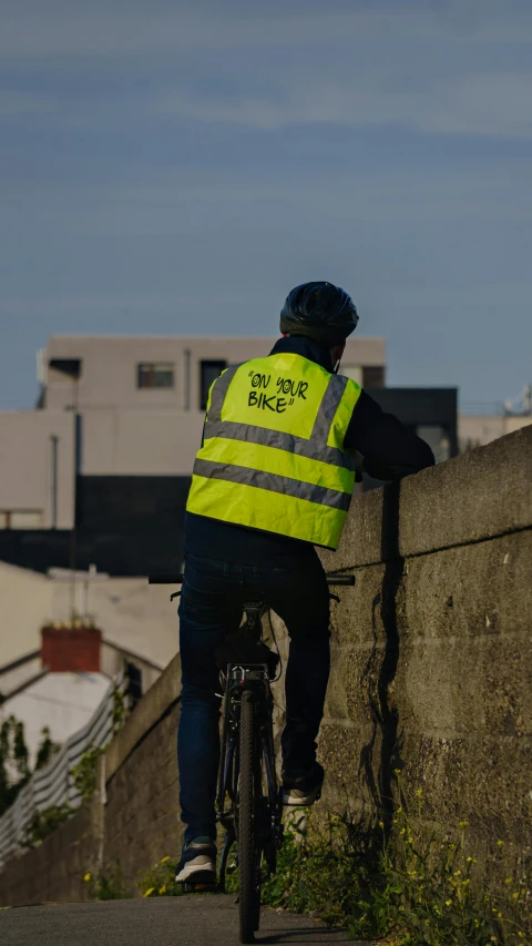 a person on a bicycle that is wearing a yellow safety vest