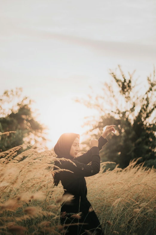 a young person wearing a jacket and reaching out to the sky