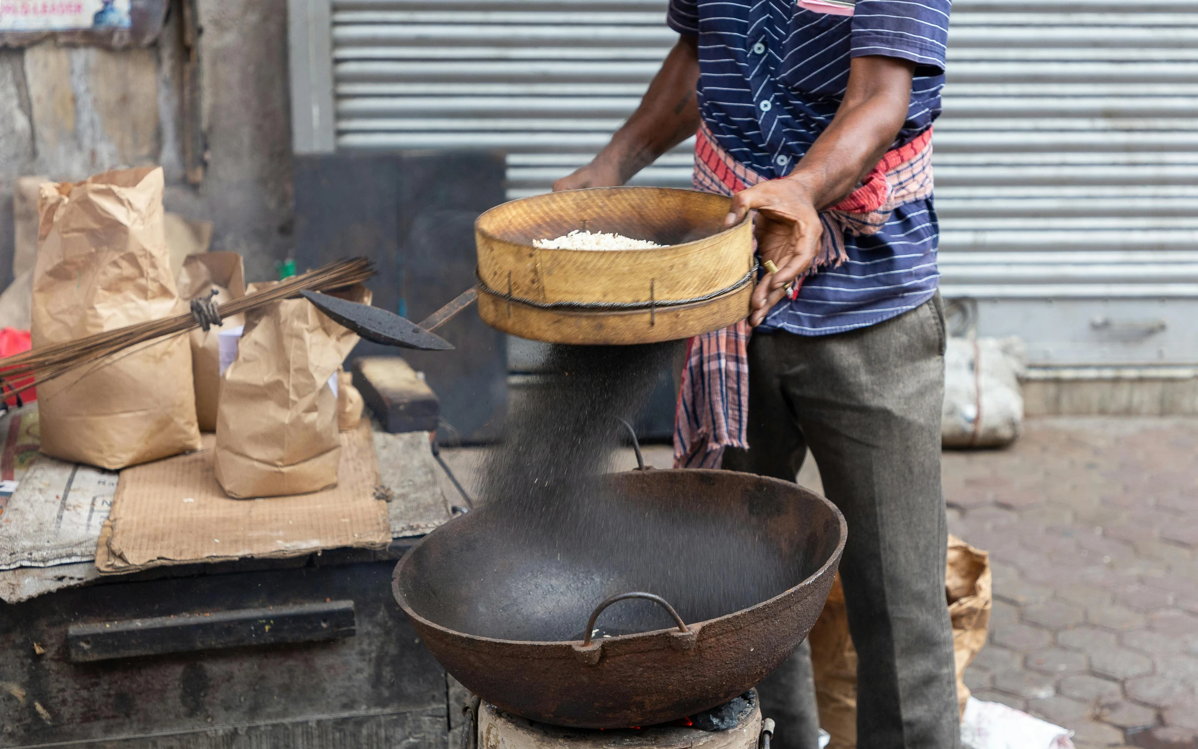 a man in a blue shirt and brown bucket cooking food