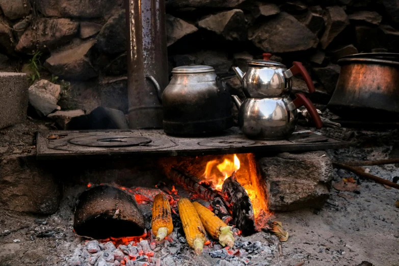 a grill with pots on it has wood burning