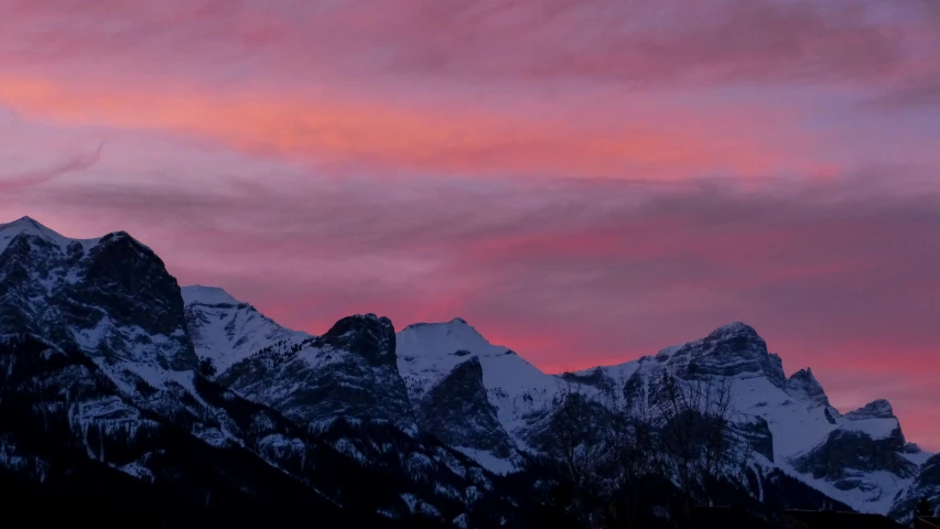 the top of a mountain covered in snow and red clouds