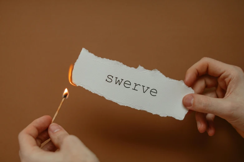 someone holding a lit match and pointing at the word swerve