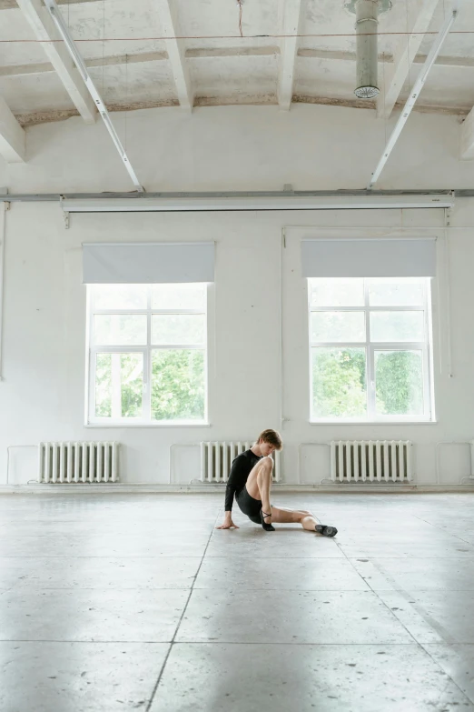 a girl with short hair sitting on the ground in an empty room