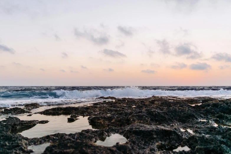 some waves crash against a rock and the sunset