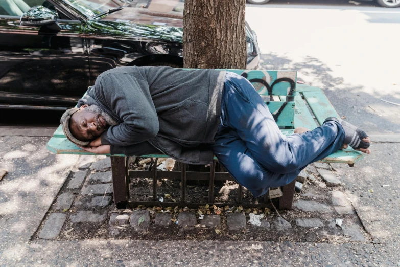 a man asleep on a bench near a street