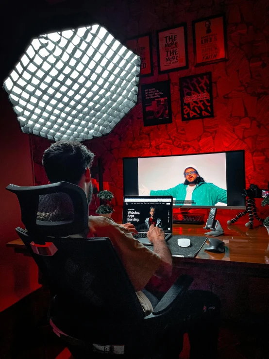 a man sitting in a chair on a laptop, and an object is projected from a screen