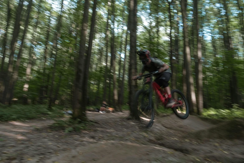 man jumps in the air on his bike through the forest