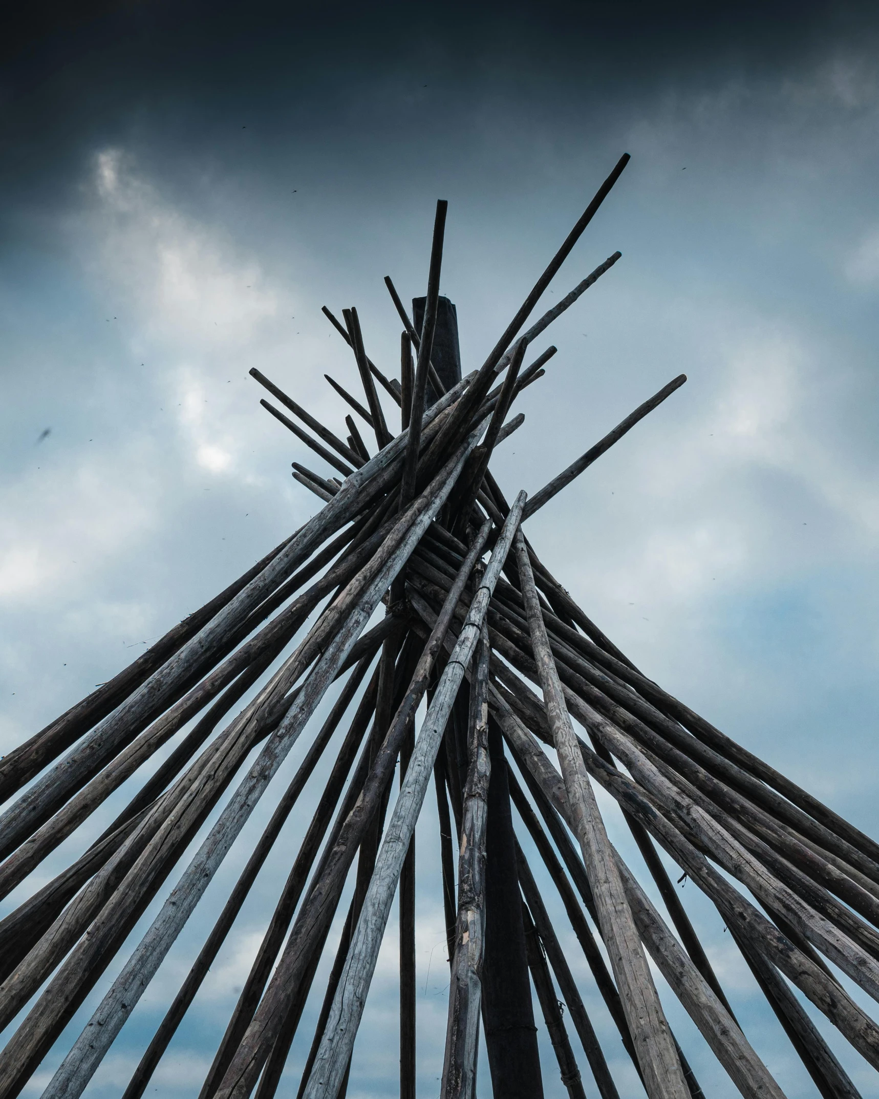 the structure of poles stands in front of a cloudy sky