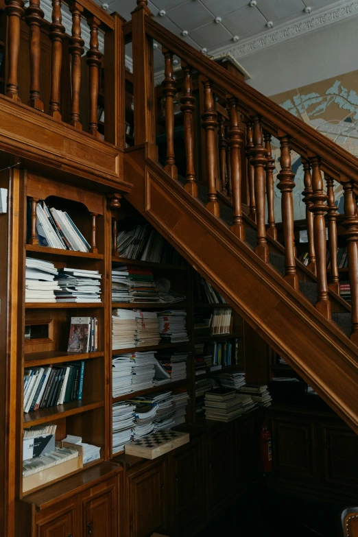 a book case under a wooden stair case