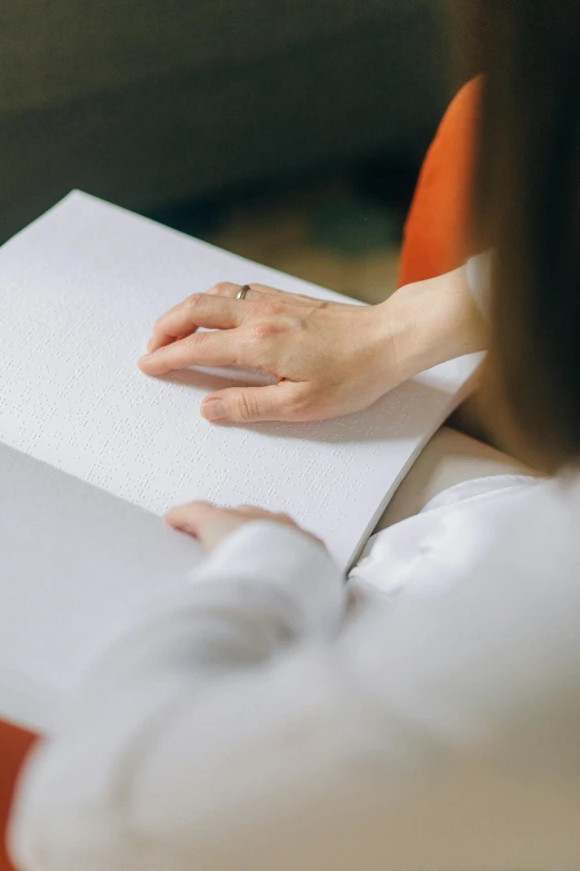 a woman holding a paper while sitting on top of an orange chair