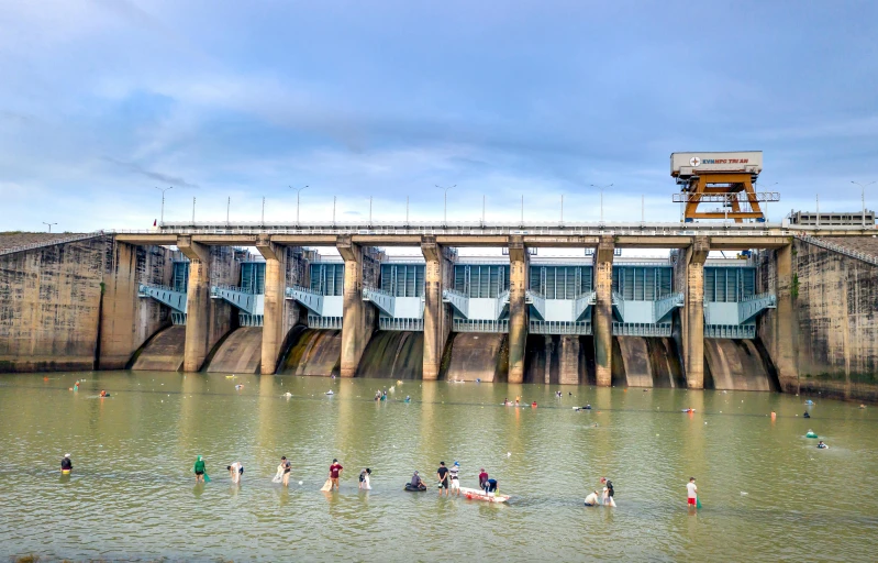 people are playing in the water by the side of the dam