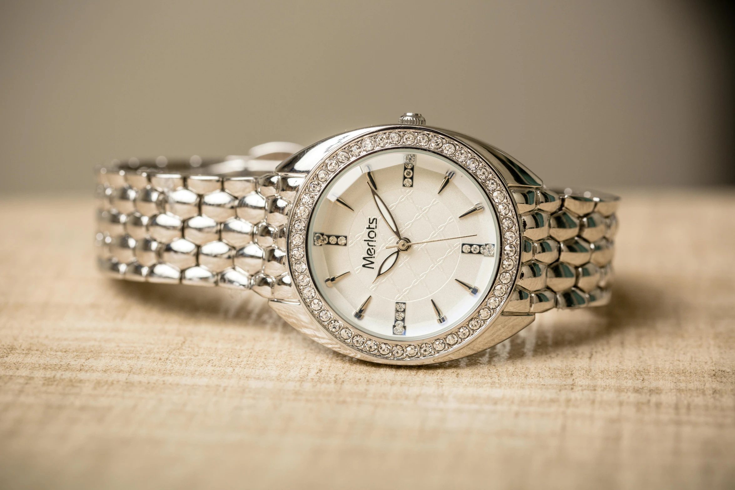 an elegant silver watch sits on a beige surface