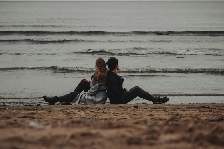 a man and a woman are sitting on the beach