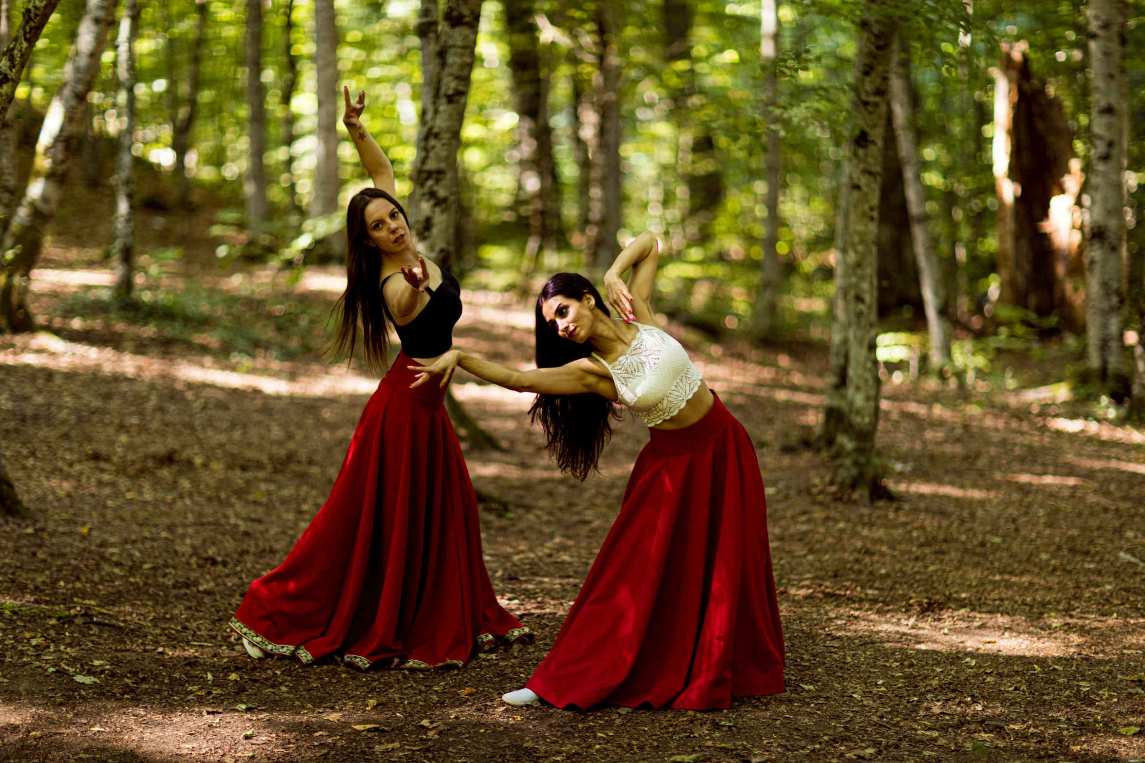 two woman dancing in the forest together