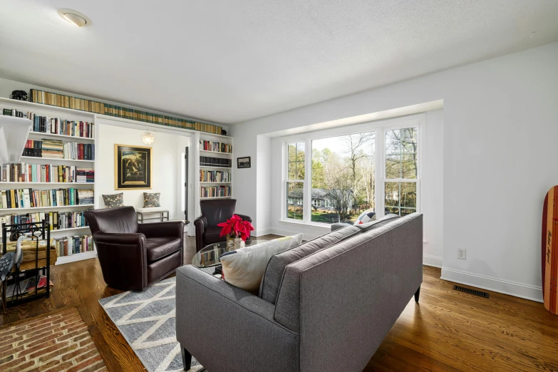 a living room with a very tall bookcase next to the window