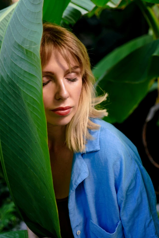 a woman is hiding in a large plant leaf