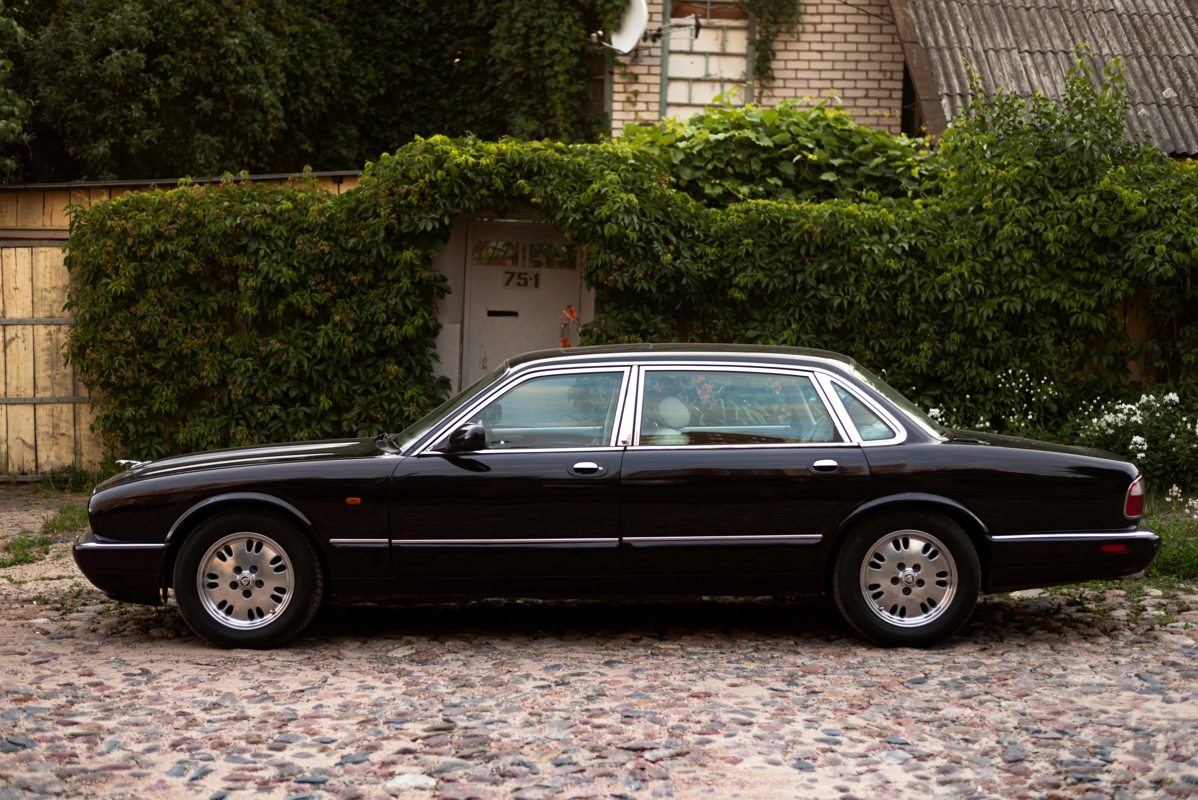 a black mercedes 600 cab sits outside in front of a brick building